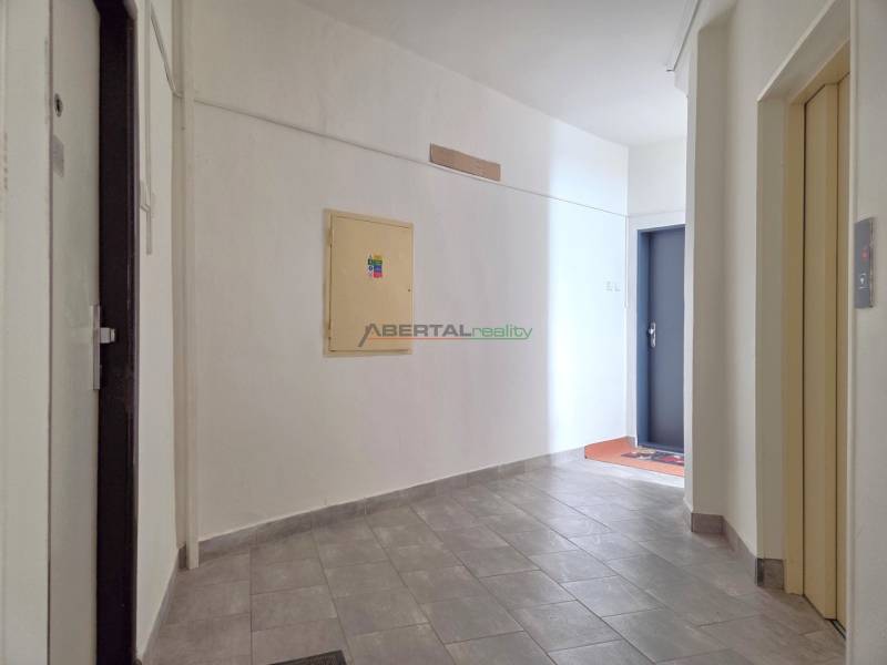 Egy 3 szobás lakás folyosója világos falakkal és szürke csempével.