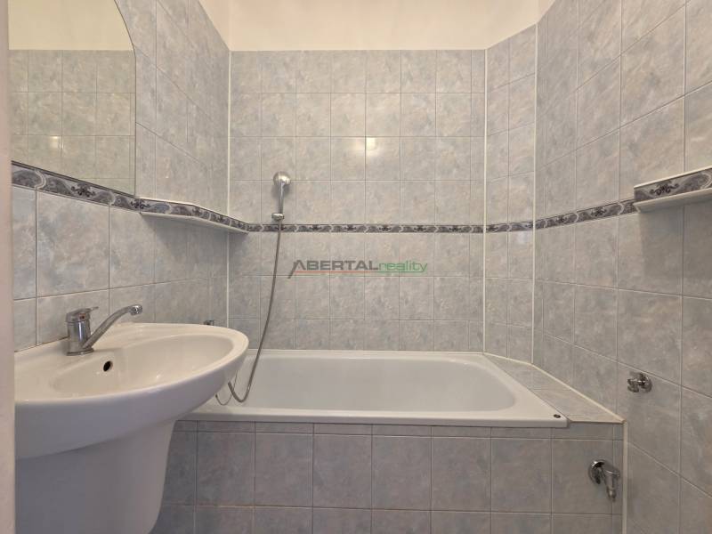 Fürdőszoba káddal egy háromszobás lakásban, világos kerámialapokkal burkolva.