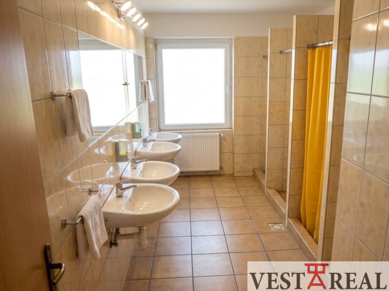A fürdőszoba az épületben mosdókkal és zuhanyzókkal rendelkezik, csempézett padlóval.