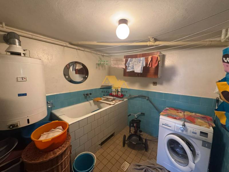 Fürdőszoba családi házban káddal, mosógéppel és bojlerrel, kék csempékkel.