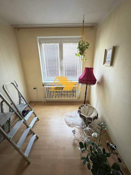 Szoba fa mintázatú padlóval, növénnyel és rózsaszín lámpával.