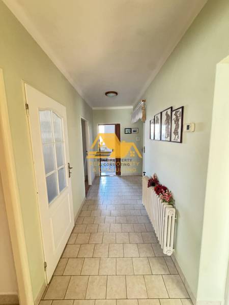 Családi ház folyosója csempézett padlóval és egyszerű dekorációval a falakon.