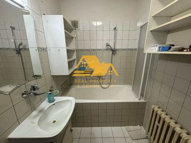 Fürdőszoba káddal, mosdóval, fehér szekrényekkel és radiátorral egy családi házban.