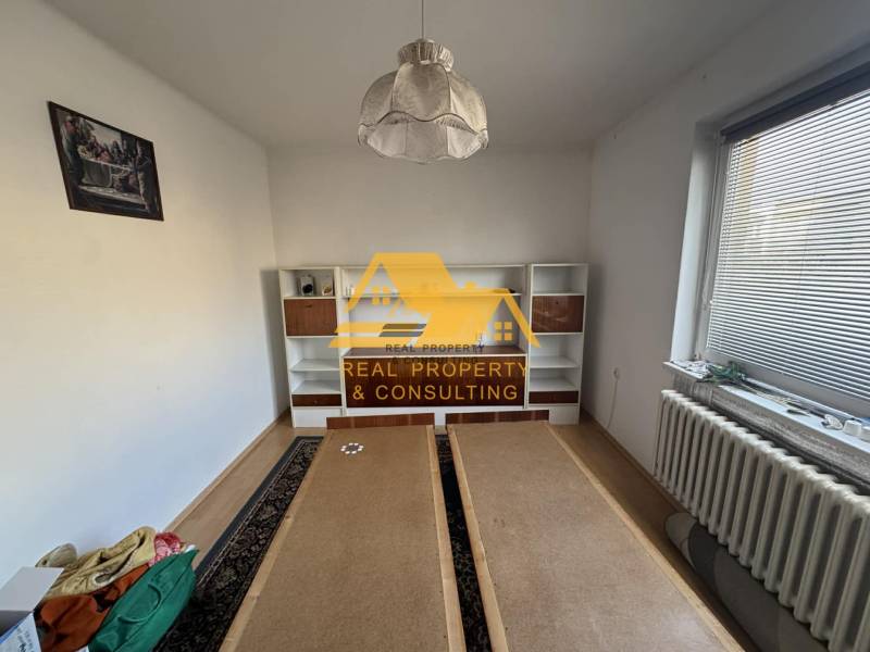 Szoba fehér fallal, polcos szekrénnyel és fa dekoros padlóval egy családi házban.