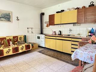 Családi ház konyhája bézs színű konyhaszekrényekkel és cserépkályhával.