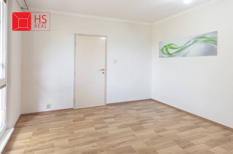 Üres szoba dekoratív képpel és fa mintázatú padlóval egy háromszobás lakásban.