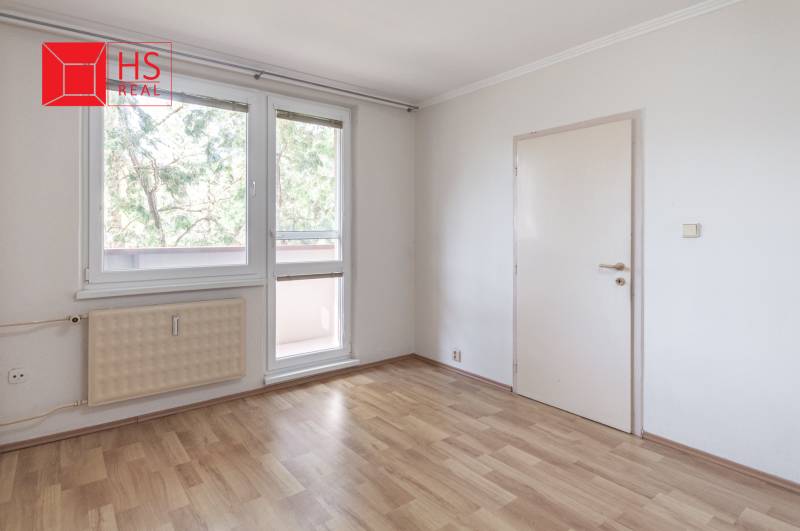 Szoba egy háromszobás lakásban, fa dekoros padlóval és nagy ablakokkal.