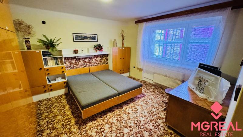 Szoba egy háromszobás lakásban fa dekorációjú bútorokkal és szőnyeggel a padlón.