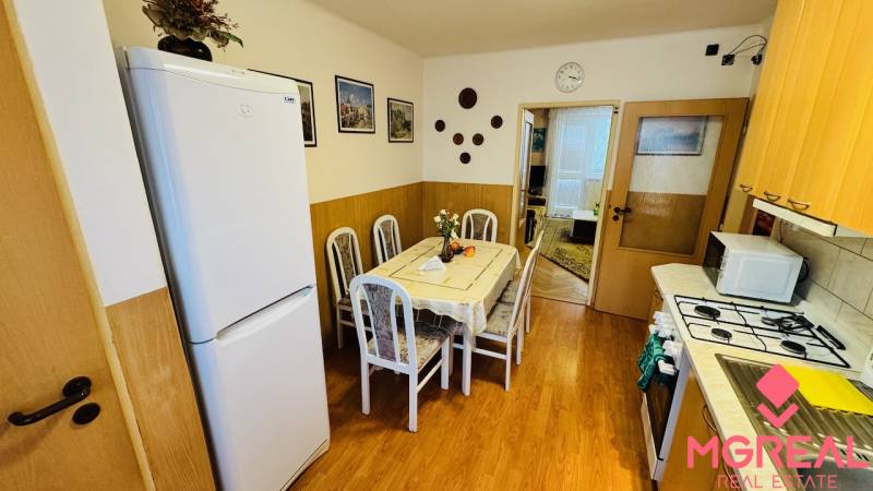 Konyha egy 3 szobás lakásban étkezőasztallal és fa dekorációjú padlóval.