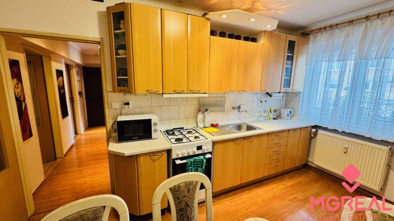 Konyha egy háromszobás lakásban, fa dekorációjú konyhapulttal és padlóval.