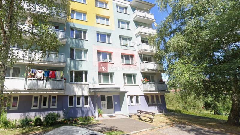 Színes lakóház a Beskydská 9-en Besztercebányán, zölddel körülvéve.