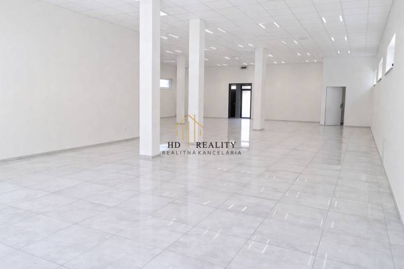 Tágas kereskedelmi helyiségek fehér padlóval és oszlopokkal, ideális vállalkozás számára.