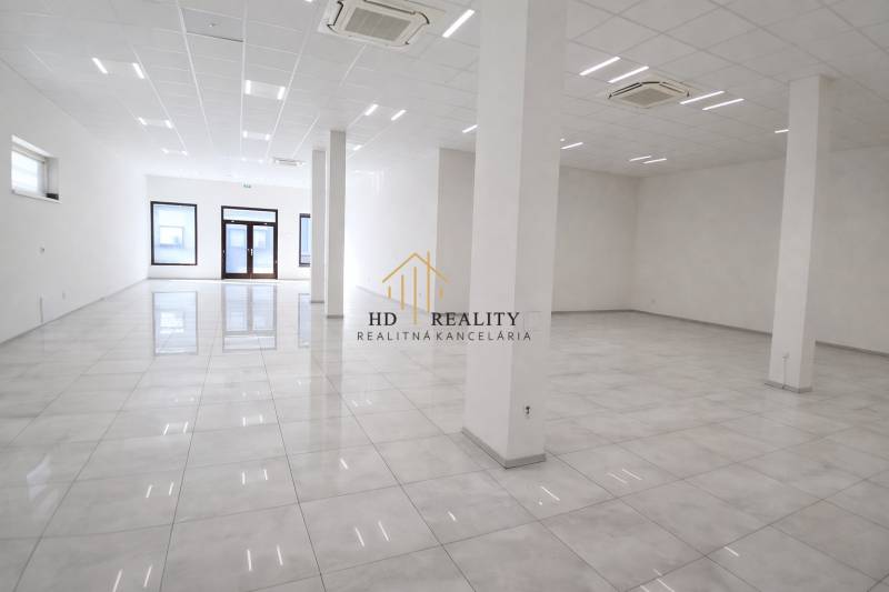 Tágas üzlethelyiségek fehér falakkal és fényes padlóval.