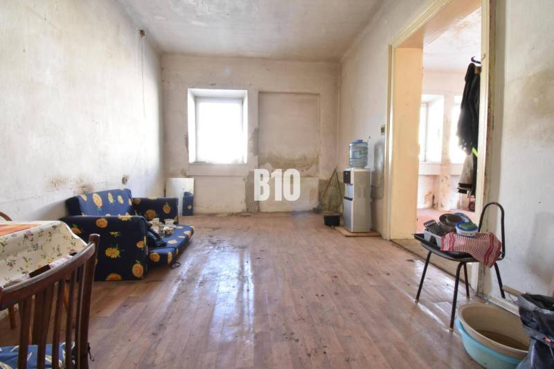 Nappali egy családi házban fa mintázatú padlóval, régebbi bútorokkal.