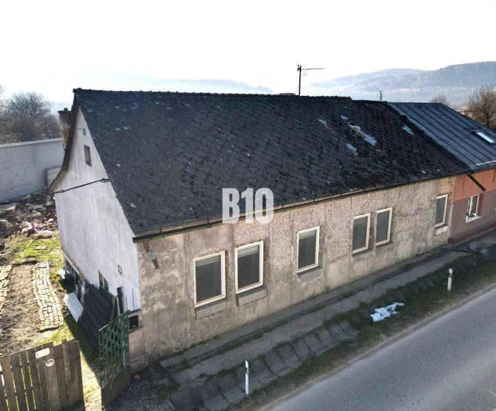 Családi ház Nagybiccseben kopott tetővel és vakolattal, főút mellett.