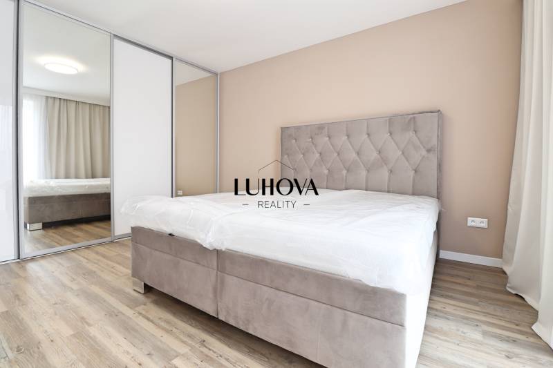 Hálószoba egy háromszobás lakásban kényelmes ággyal, beépített szekrénnyel és fa dekorációjú padlóval.