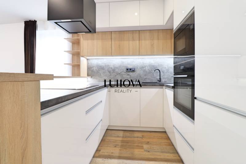 Konyha egy háromszobás lakásban fehér szekrényekkel és fa dekor padlóval.