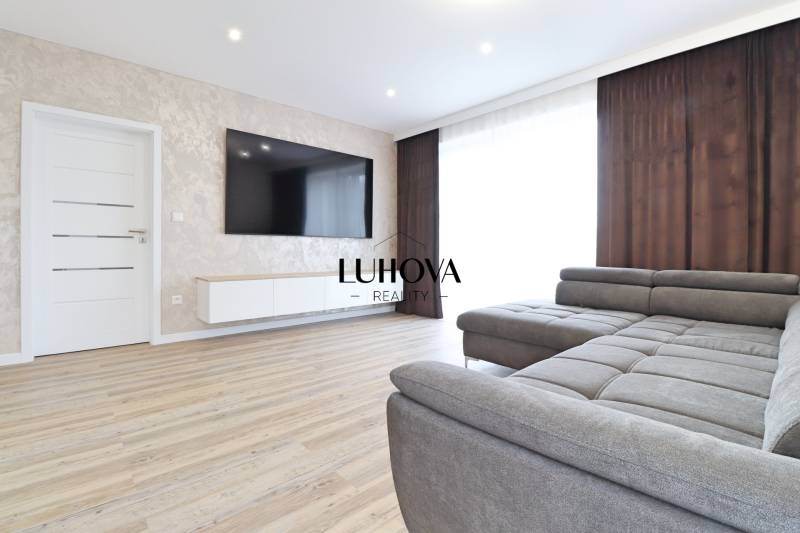 Nappali egy háromszobás lakásban kanapéval és fa dekorációjú padlóval.