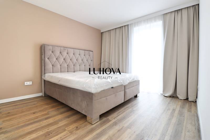 Hálószoba ággyal és fa dekorációjú padlóval egy háromszobás lakásban.