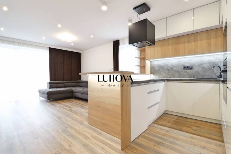 3 szobás lakás belső tere konyhával, kanapéval és fa dekorációjú padlóval.