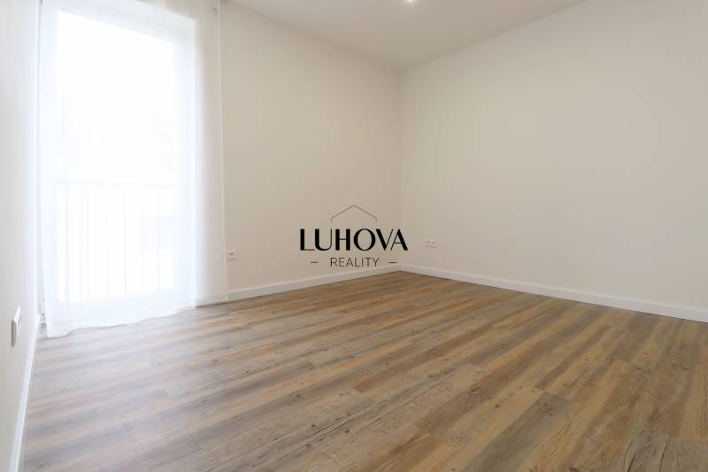 Szoba egy háromszobás lakásban, fa dekorációjú padlóval és egyszerű dizájnnal.