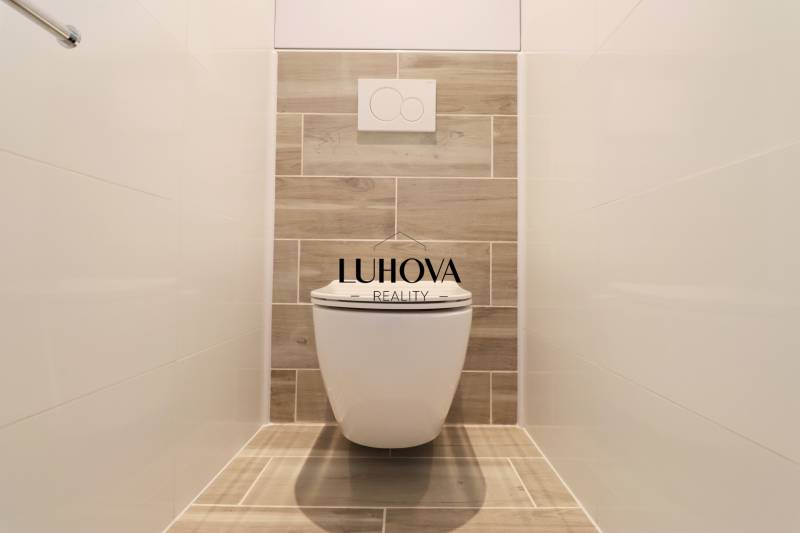 Fa dekorral és fehér csempékkel ellátott WC egy háromszobás lakásban.