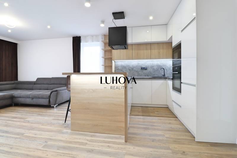 Nappali konyhával és fa dekoros padlóval egy háromszobás lakásban.