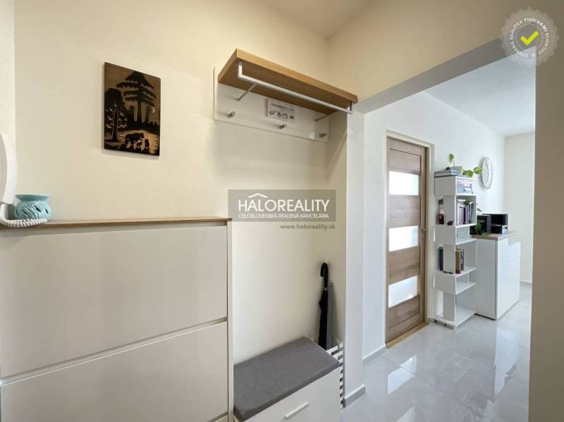 1 szobás lakás belső tere fogassal, cipősszekrénnyel és polcokkal az ajtó mellett.