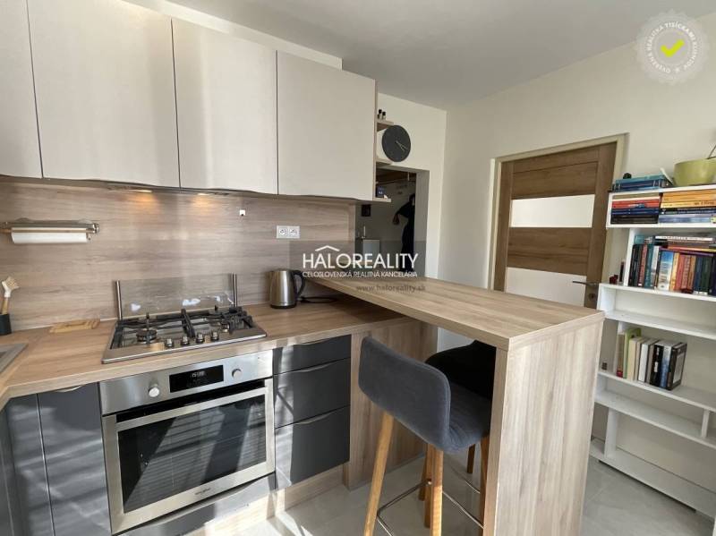 Egyszobás lakás konyhája konyhapulttal és háztartási gépekkel.