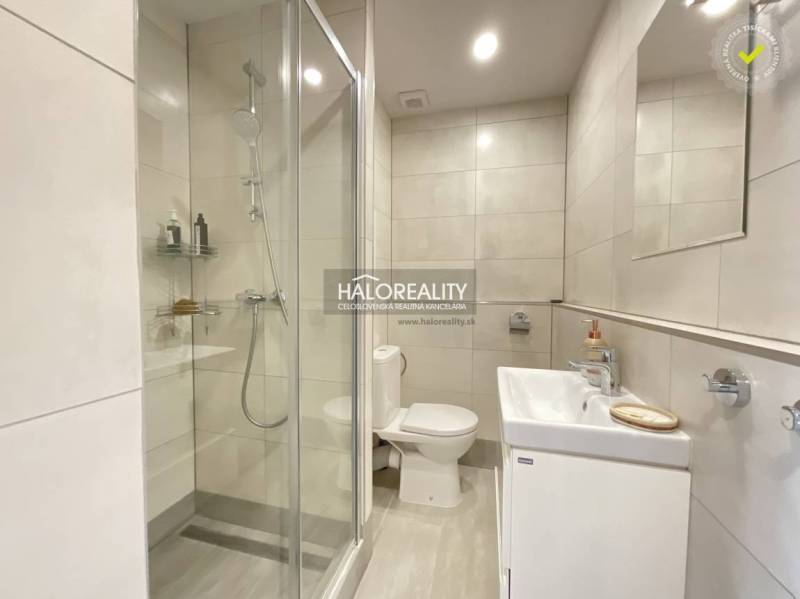 Fürdőszoba egy egyszobás lakásban káddal, zuhanyzóval és mosdóval.