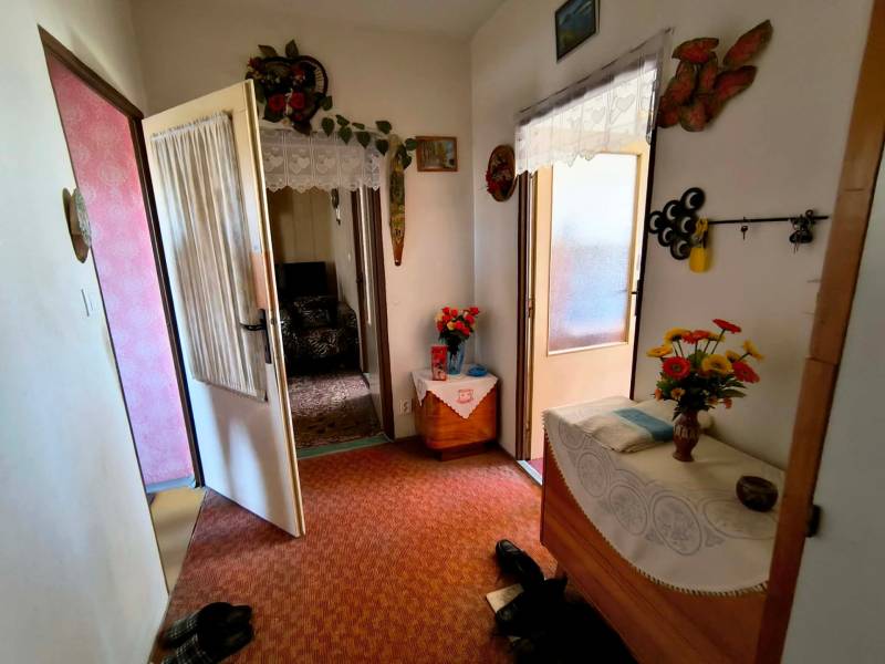 3 szobás lakás előszobája szőnyeggel, bútorokkal és dekorációként virágokkal.