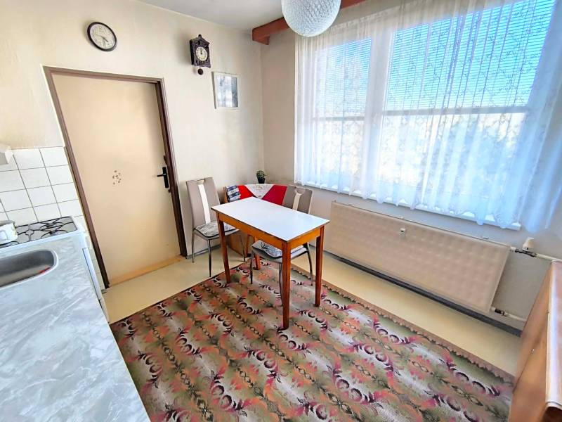 Konyha egy háromszobás lakásban étkezőasztallal, székekkel és szőnyeggel.