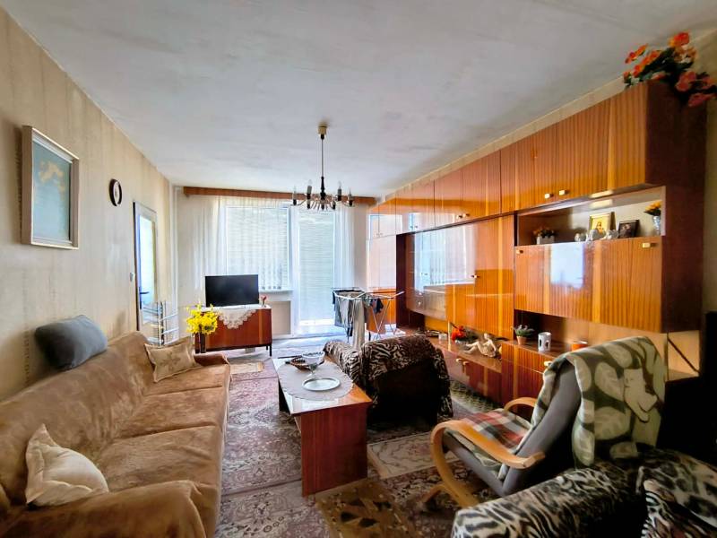 Nappali egy háromszobás lakásban, fa dekoros padlóval és ülőgarnitúrával.