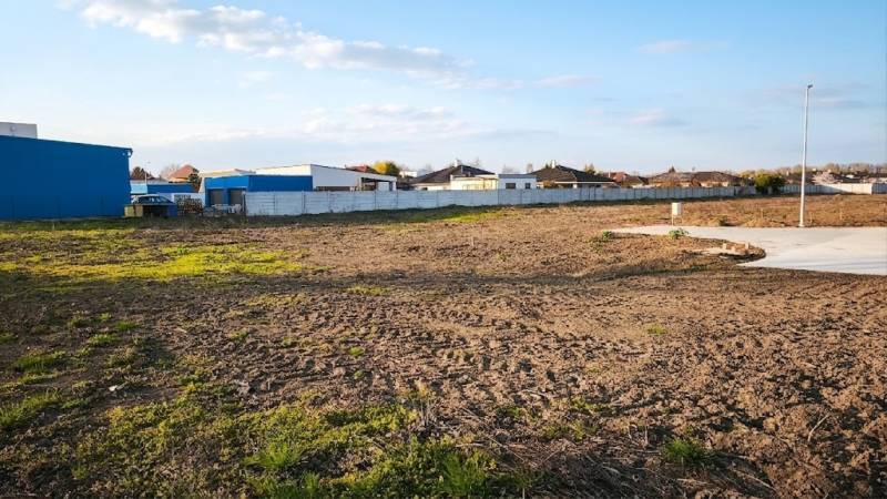 Kereskedelmi területek Vágkirályfán kiterjedt nyílt területtel és bekerített épületekkel.