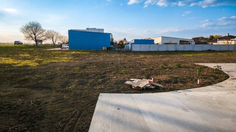 Kereskedelmi telkek Királyrévben, aszfaltos terület, épület és zöldterület.