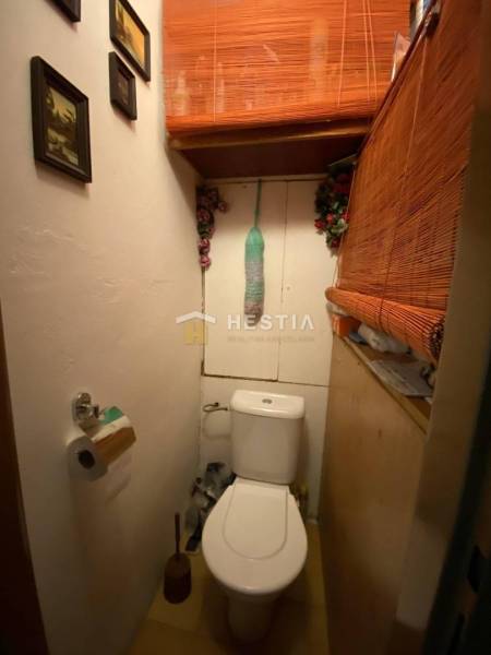 Kis WC a kétszobás lakásban dekoratív bambusz elemekkel és képekkel a falon.