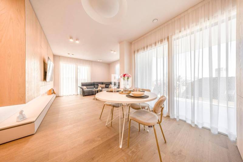 Nappali egy háromszobás lakásban, fa dekorációjú padlóval, étkezőasztallal és kanapéval.