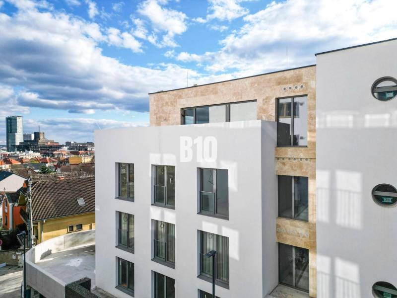 Fehér épület nagy ablakokkal Pozsony III-ban, a Matúškova utcában, háromszobás lakással.