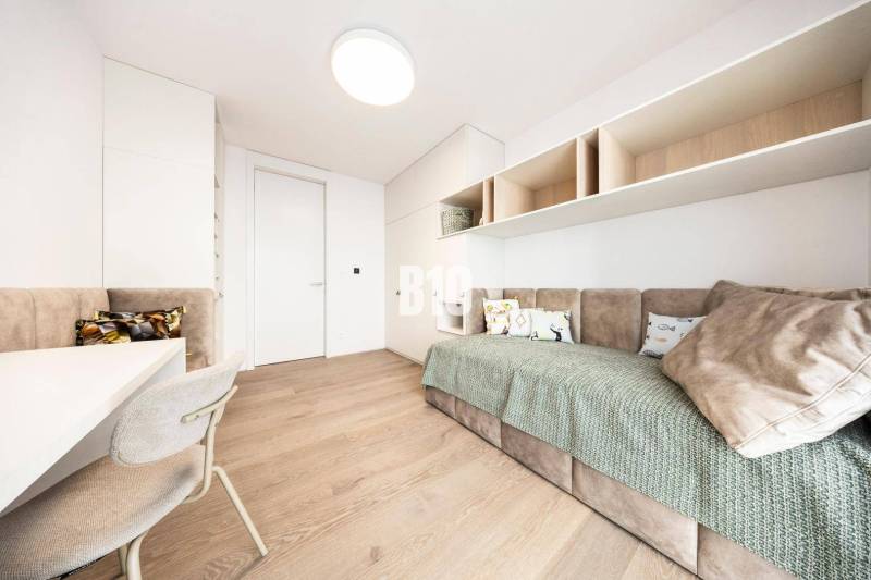 Minimalista szoba kanapéval, világos bútorokkal és fa dekorációjú padlóval egy háromszobás lakásban.