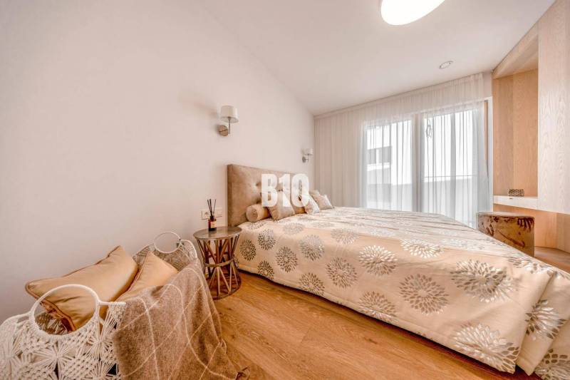 Hálószoba egy háromszobás lakásban, fa mintázatú padlóval és ággyal.