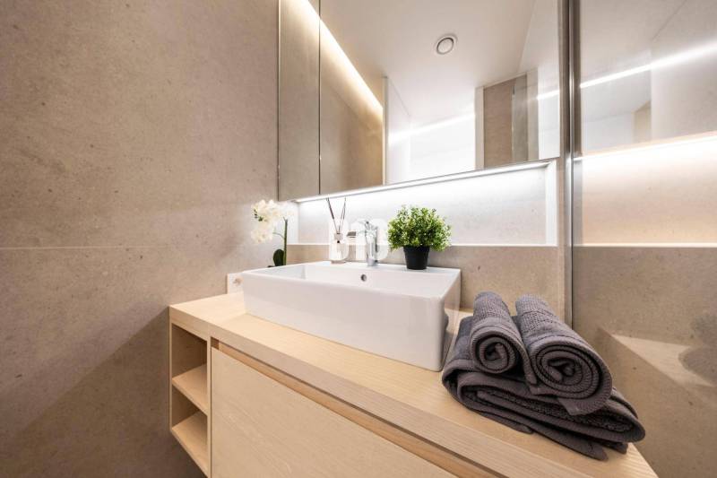 Fürdőszoba modern mosdóval, törölközőkkel és dekorációval egy háromszobás lakásban.