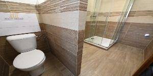Fürdőszoba kétszobás lakásban WC-vel és fa dekorációs csempével.