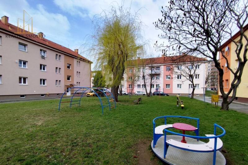 Játszótér mászókákkal és fákkal a Békesség utcában, egy kétszobás lakás előtt.