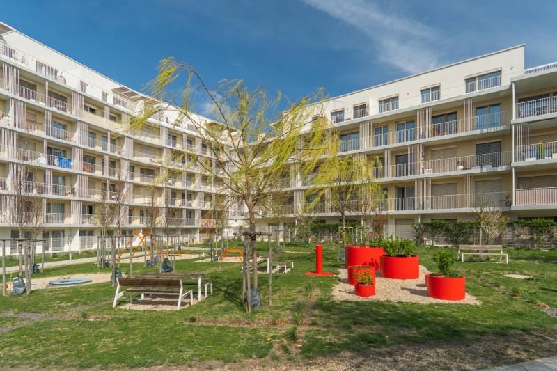 Kilátás egy lakóépületre és udvarra játszótérrel Pozsony-Ružinovban.