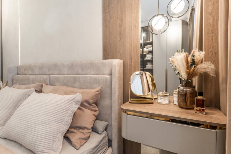 Hálószoba egy háromszobás lakásban ággyal, tükörrel és dekoratív elemekkel.