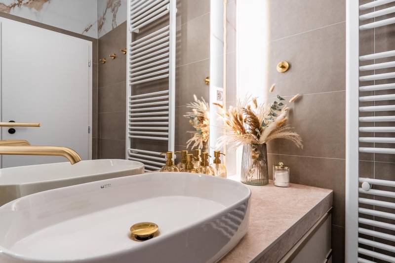 Fürdőszoba arany részletekkel és dekorációval egy háromszobás lakásban.