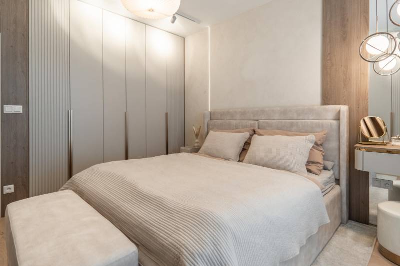 Világos hálószoba beépített szekrénnyel és ággyal egy háromszobás lakásban.