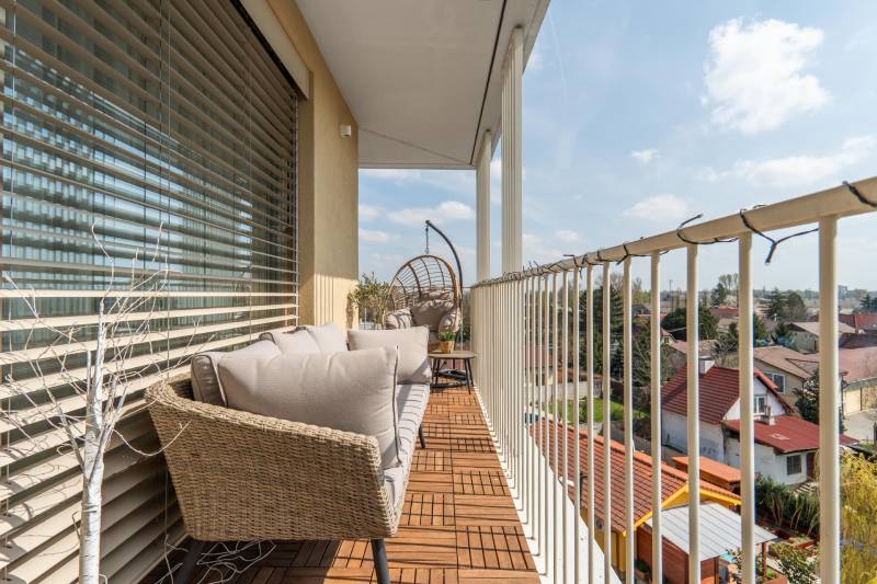 Egy háromszobás lakás erkélye Pozsonyban - Ružinovban, kültéri ülőgarnitúrával és fa dekorációval.