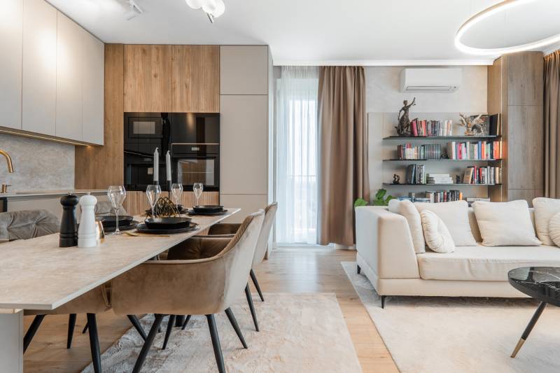 Háromszobás lakás nyitott tere konyhával, étkezőasztallal és kényelmes nappali sarokkal.