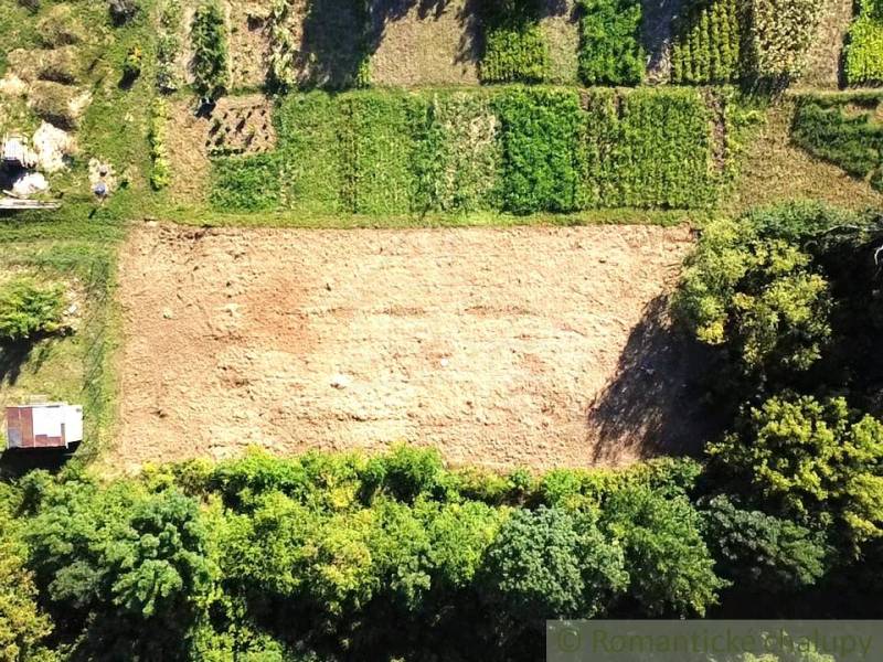 Lakóövezeti telkek Hosťován, rét a környező zöld parcellákkal, madártávlatból látható.